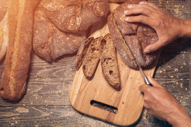 istock mans hands cutting slices of fresh brown bread; 1024140398