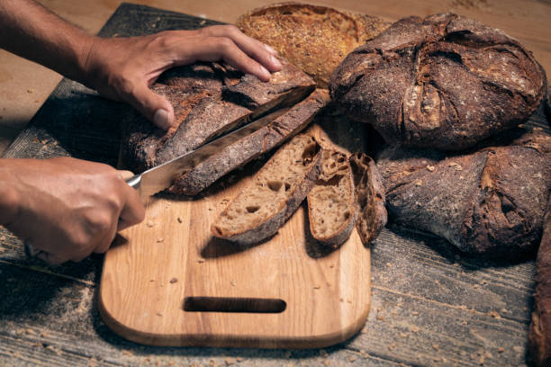 istock mans hands cutting slices of fresh brown bread; 1024140420