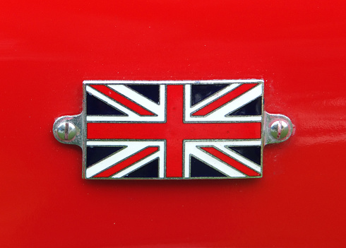 a Union Jack metal badge detail on a vintage red sports car