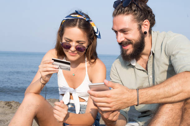 istock Two young people online shopping at the beach 1024157224