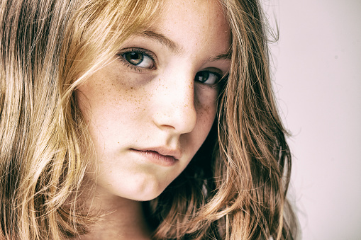 Headshot of a 10 years old girl making a sad face.