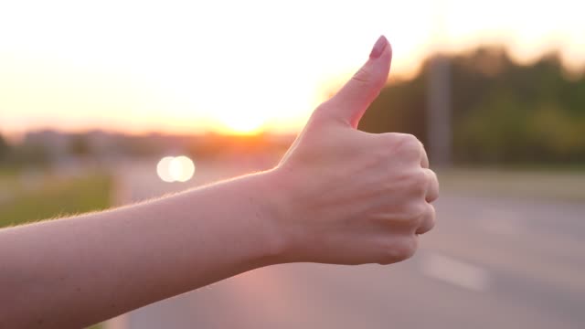 Woman hand catch car on road, thumb up, hitchhiking concept