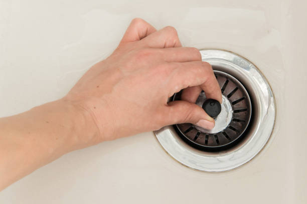 woman hand pulls close cap of drainage hole of sink to drain water - colander imagens e fotografias de stock