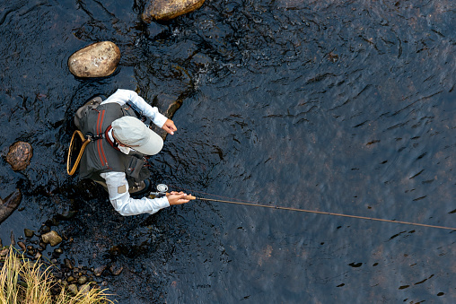 Fly fisherman using flyfishing rod in beautiful river