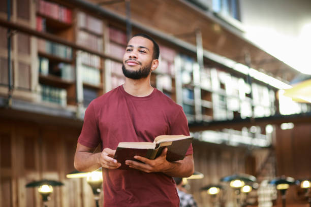 図書館で本を読んで若い男 - bookshelf beautiful intelligence learning ストックフォトと画像