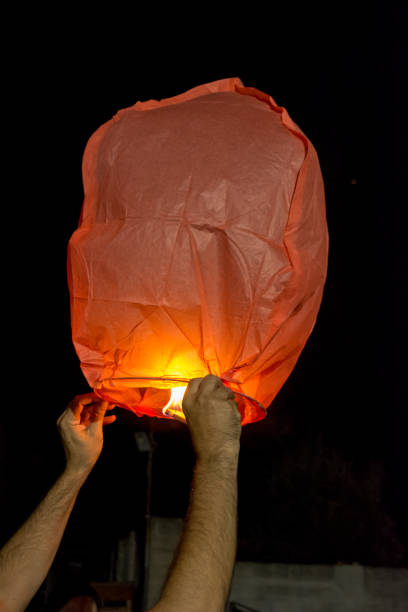 istock Hands Holding a Chinese Flying Lantern before Flying on Dark Background 1024183064
