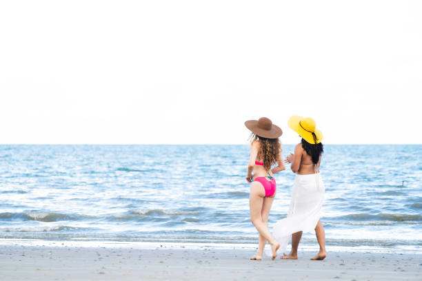 istock Happy women go sunbathing at sand beach in summer. 1024183674