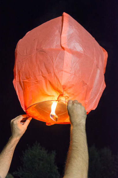 istock Hands Holding a Chinese Flying Lantern before Flying on Dark Background 1024188014