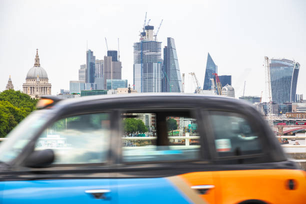 Concept, London cityscape with a black cab in motion at the foreground