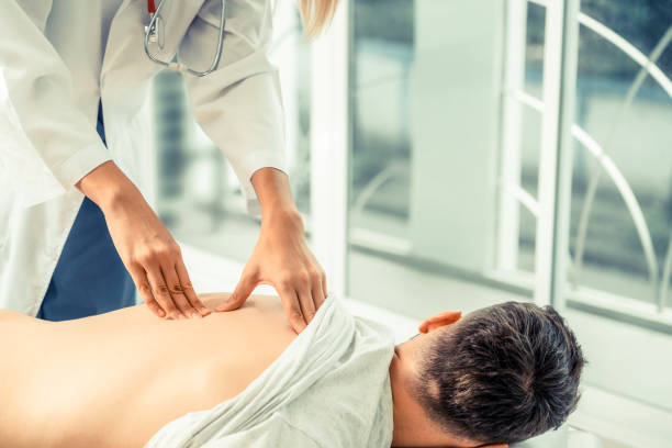 woman doctor and male patient in hospital office - physical injury backache occupation office imagens e fotografias de stock