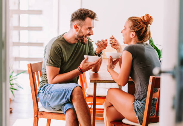 Young couple eating cereal breakfast at dining room table