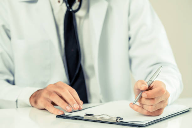 Doctor in hospital writing on a paper document.