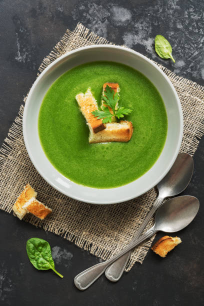 istock Green cream soup with spinach on a concrete dark background. Overhead, top view, flat lay. 1024208816