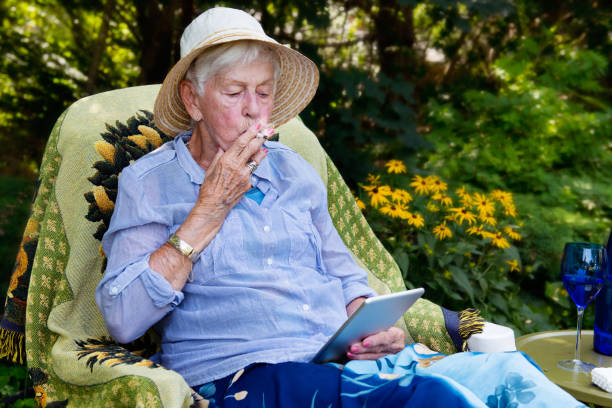 Happy senior woman smoking marijuana joint as cannabis medicinal stock photo