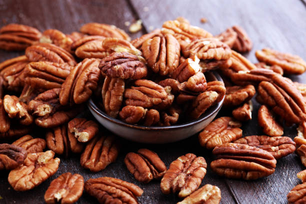 istock Pecan nuts on a rustic wooden table and pecan nuts in bowl 1024220692