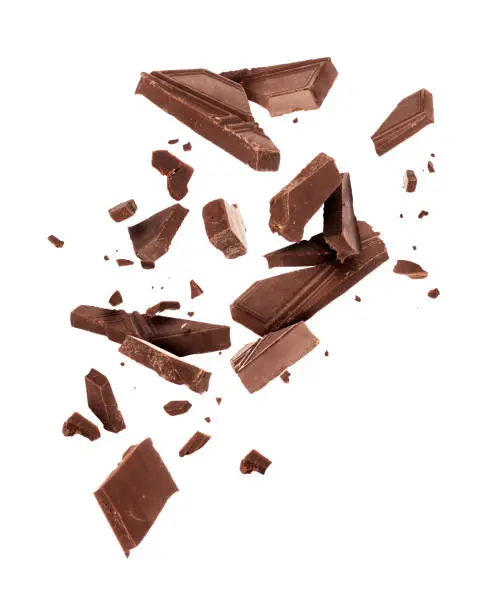 Photo of Pieces of dark chocolate falling close up on a white background