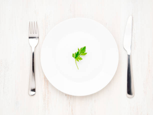 istock Parsley on empty white plate, fork and knife on a white wooden table, top view, diet concept 1024230156