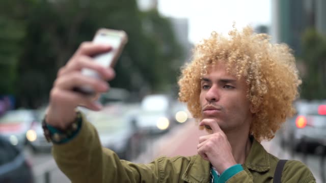 Fashionable Men with Curly Hair Taking a Selfie