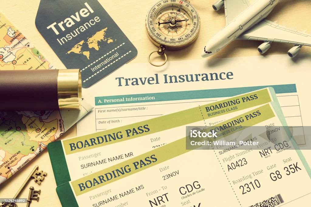 Travel insurance and travel security service concept : Top view of travel insurance application form, business class boarding passes, map, monocular, tag, compass, white model air plane on wood floor. Insurance Stock Photo