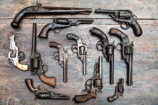 Armory display of historic guns and pistols in a overhead view on a vintage wooden table background