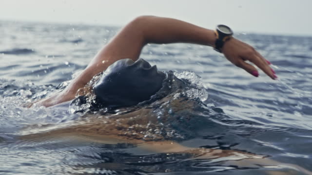 Slow motion medium tracking shot of a female swimmer swimming the forward crawl in the ocean. Shot in Slovenia.