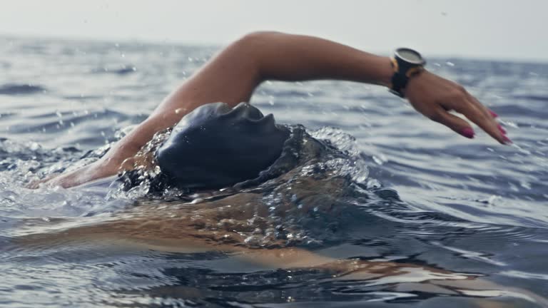 Slow motion medium tracking shot of a female swimmer swimming the forward crawl in the ocean. Shot in Slovenia.