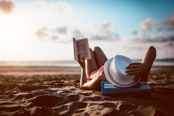 istock Beautiful Female Reading A Book On The Beach During Sunset 1024274040