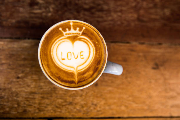 Tasty cappuccino is on the wooden texture table with love art