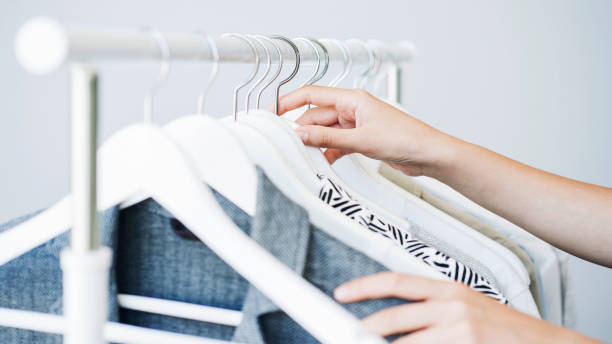 mujer escogiendo ropa en un estante - shirt hanger hanging blue fotografías e imágenes de stock