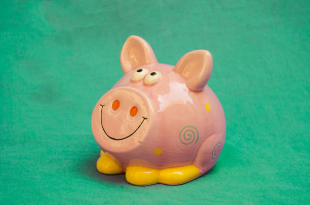 istock pink smiling piggy bank on green background 1024299562