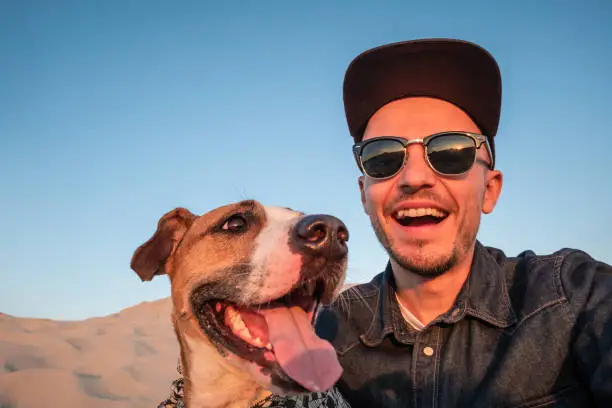 Happy young male person makes self portrait with his dog outdoors