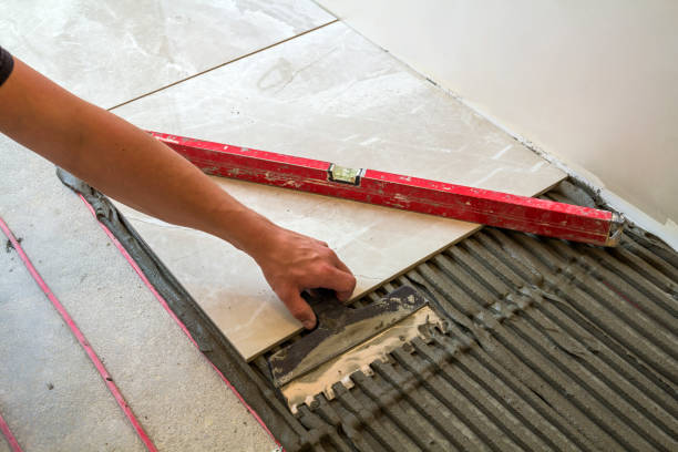 istock Ceramic tiles and tools for tiler. Worker hand installing floor tiles. Home improvement, renovation - ceramic tile floor adhesive, mortar, level. 1024313444