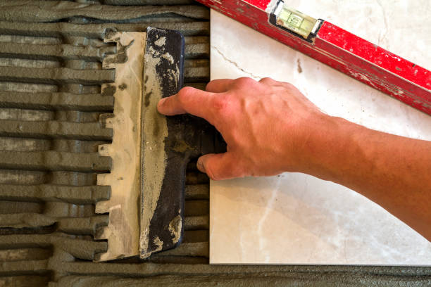 istock Ceramic tiles and tools for tiler. Worker hand installing floor tiles. Home improvement, renovation - ceramic tile floor adhesive, mortar, level. 1024313510