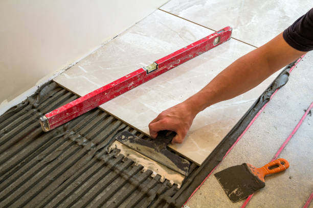 istock Ceramic tiles and tools for tiler. Worker hand installing floor tiles. Home improvement, renovation - ceramic tile floor adhesive, mortar, level. 1024313572