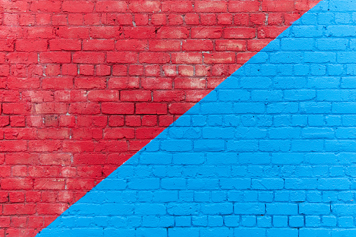 A photograph taken of the exterior wall of a building in the city. The colours red and blue are divided diagonally.
