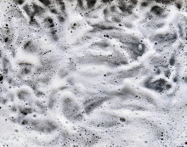White foam and soap on dark background. Abstract pattern. stock photo