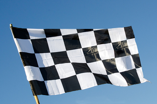 Checkered flag isolated on blue sky background. Copy space