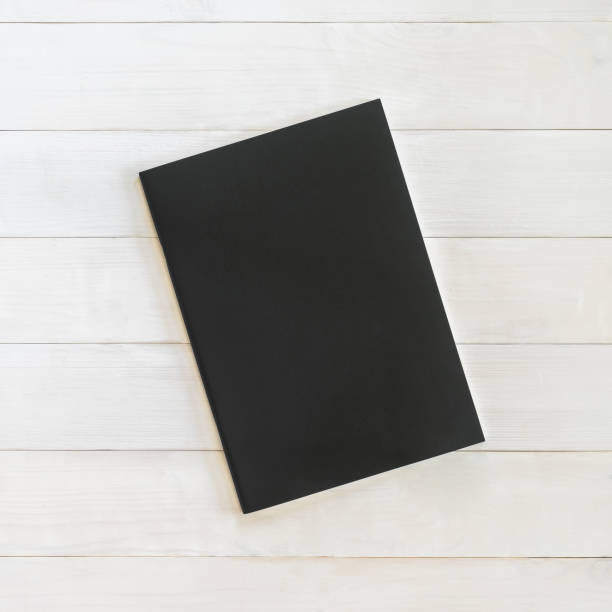 Book mockup blank black leather A4-size cover page template flat lay on white wood table from top view