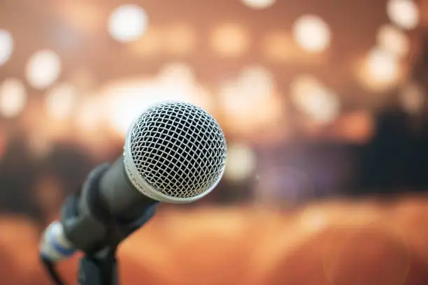 Photo of Seminar Conference Concept : Close-up Microphones on abstract blurred of speech in meeting room, front speaking blur people in event convention hall with lens light flare in hotel background
