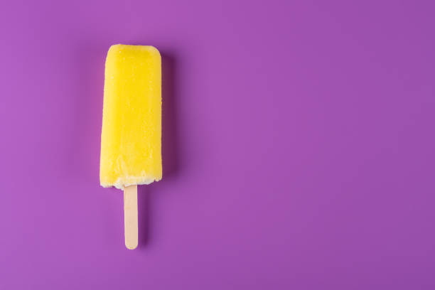 istock yellow popsicle on a purple background 1024412996
