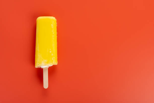 istock yellow popsicle on a red background 1024413296
