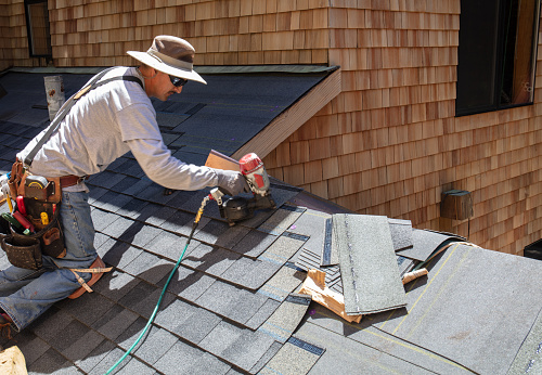 Installing new roof with  nail gun and shingles