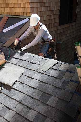 Installing new roof with  nail gun and shingles