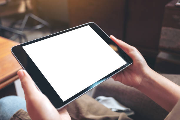 istock Mockup image of woman's hands holding black tablet pc with blank white desktop screen while sitting in cafe 1024499168