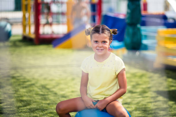 Playground and fun is all I need. Little smiling girl spending time on playground. Looking at camera. Space for copy.