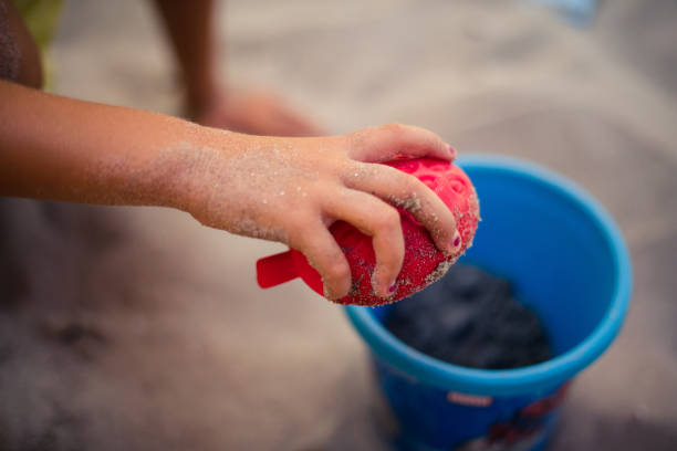 Summer is a lot of fun. Little girl playing in sand. Close up. Space for copy. Focus is on hand.