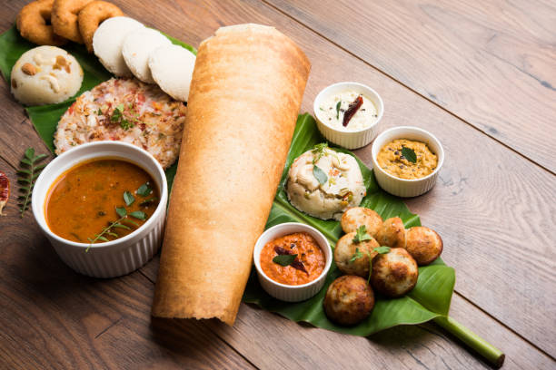 grupo de comida de la india del sur como masala dosa uttapam, idli, ocioso, ama/vada, sambar, appam, sémola halwa, upma sobre hoja de plátano acompañado de salsas picantes coloridos, enfoque selectivo - southern usa fotografías e imágenes de stock