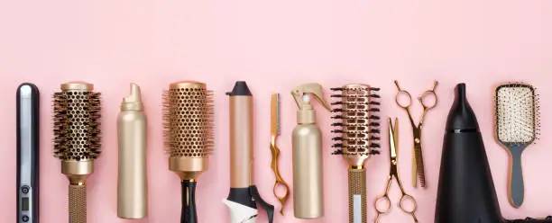 Photo of Professional hair dresser tools on pink background with copy space