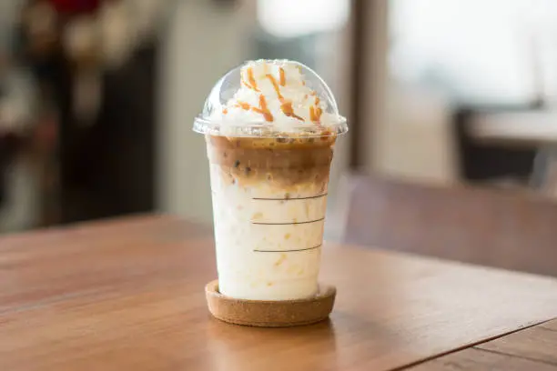 Ice coffee and whipped cream with caramel sauce on table