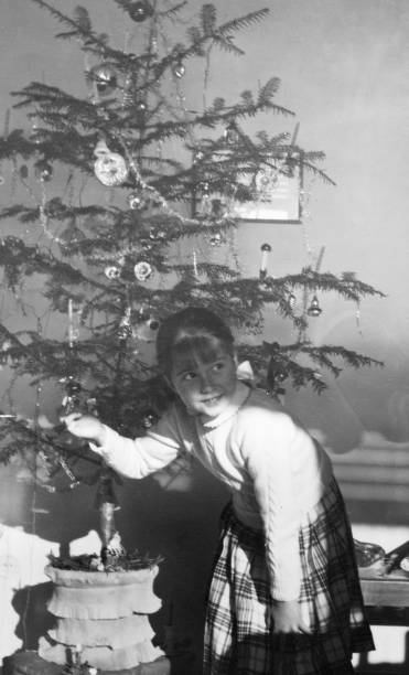 1955 female child playing with christmas tree and doll